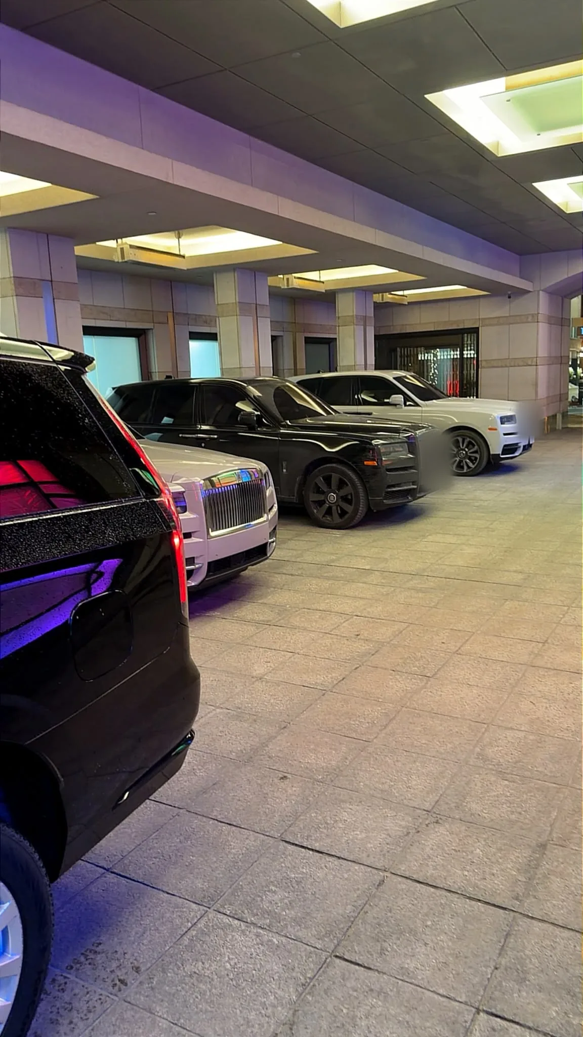 Rolls-Royce Cullinans waiting under a hotel porte-cochère at night