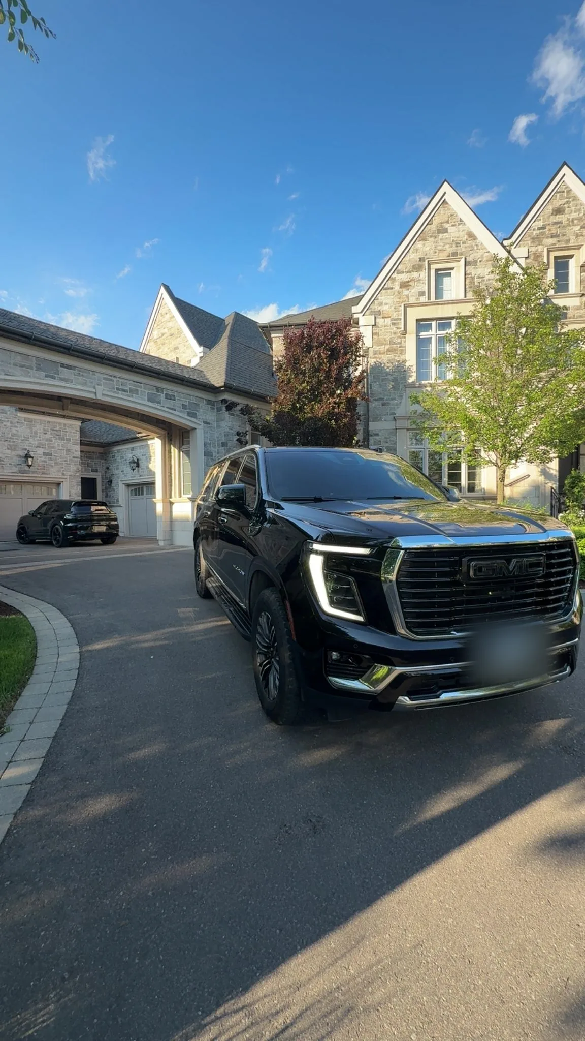 Black GMC Yukon Denali in the driveway of a stone residence